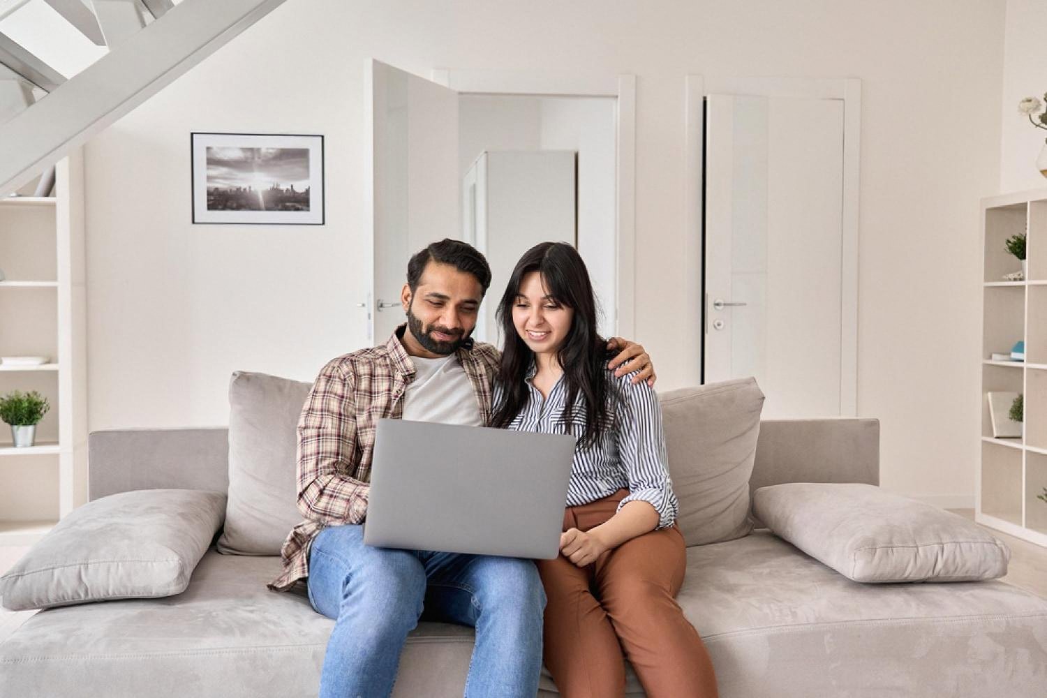 Young couple in a Dubai apartment reviewing home insurance quotes on a laptop